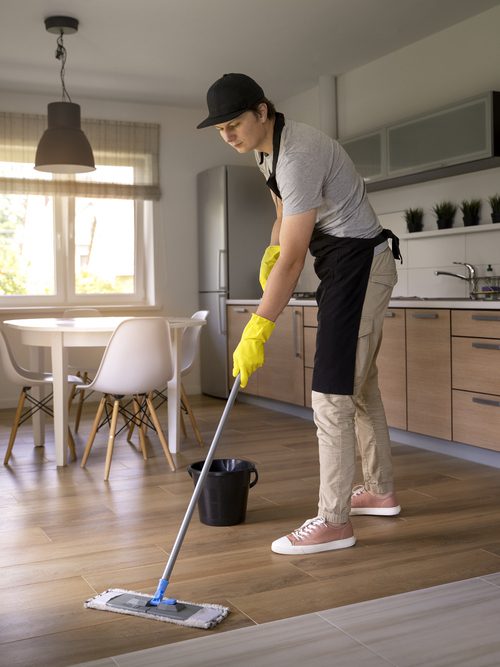 A man mopping a kitchen floor.